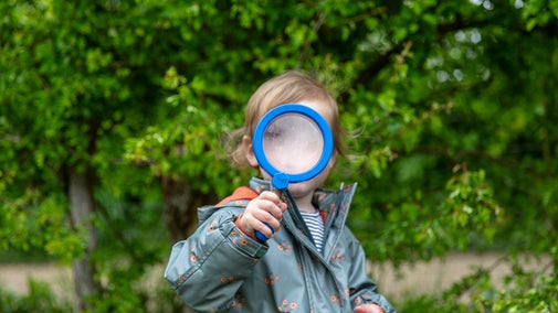 A child looks trough a magnifying glass